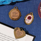 Three gold-tone magnetic bookmarks with locket designs clipped onto the pages of an open book on a blue surface.