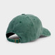 Back of washed green cotton baseball cap showing adjustable fabric strap and brass-colored metal buckle closure
