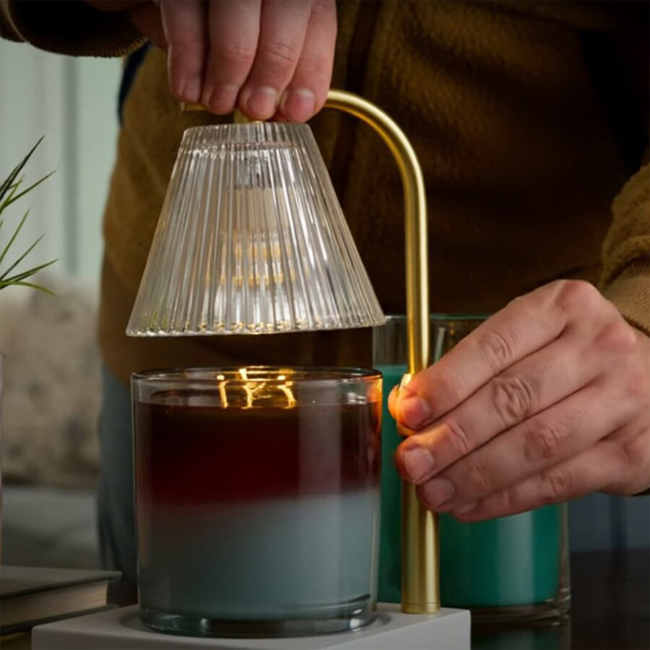A close-up showing the adjustable nature of the Gold Luna Candle Warmer Lamp being positioned over a scented jar candle to release flame-free fragrance