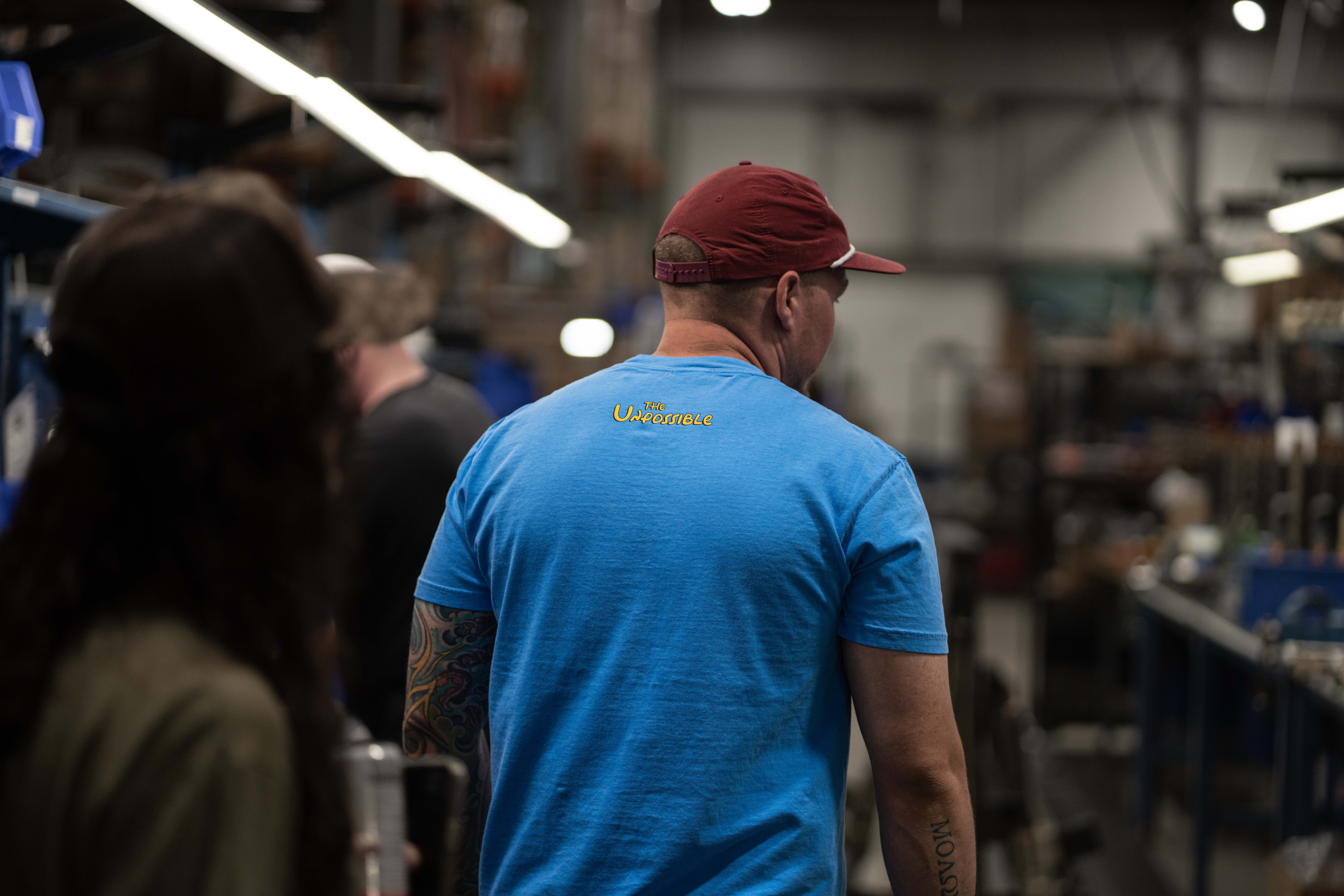 Blue Shirt with the Unpossible on the back in yellow text.