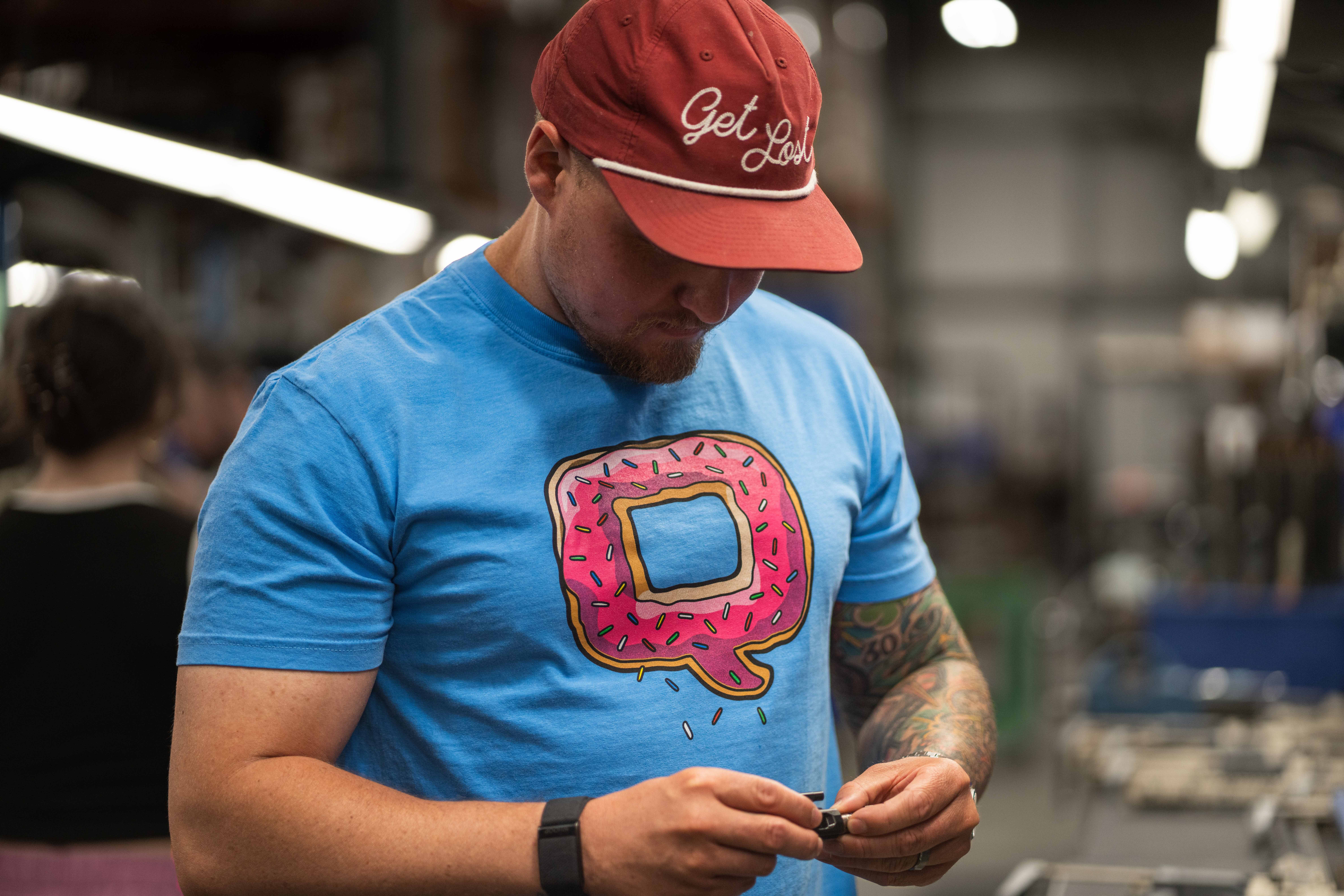 Man wearing blue shirt  with pink donut on the front.