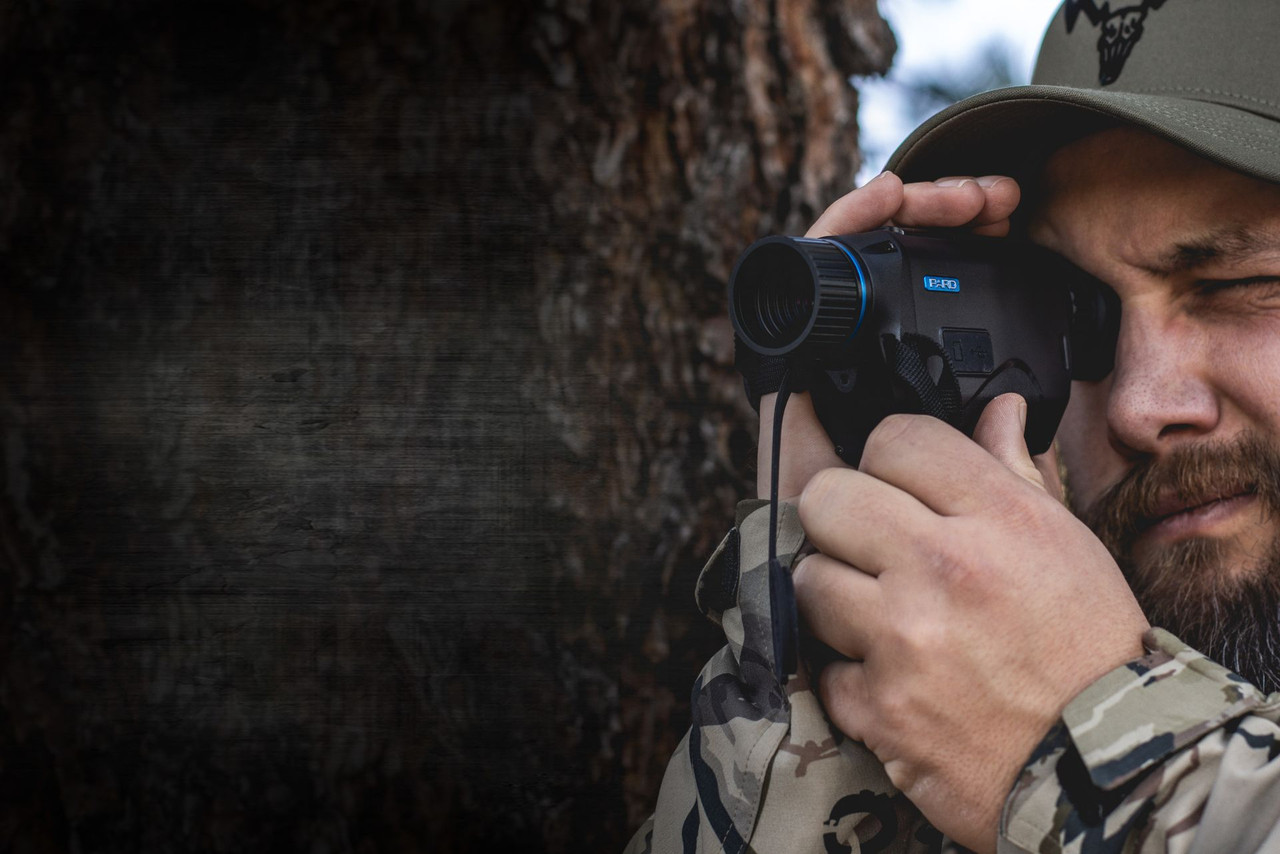 Man checking the field with a PARD handheld thermal monocular during an outdoor hunt.