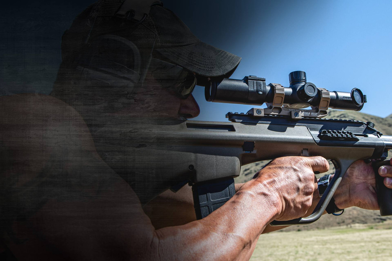 Shooter sighting in a rifle fitted with a tactical night-vision scope in an outdoor field.