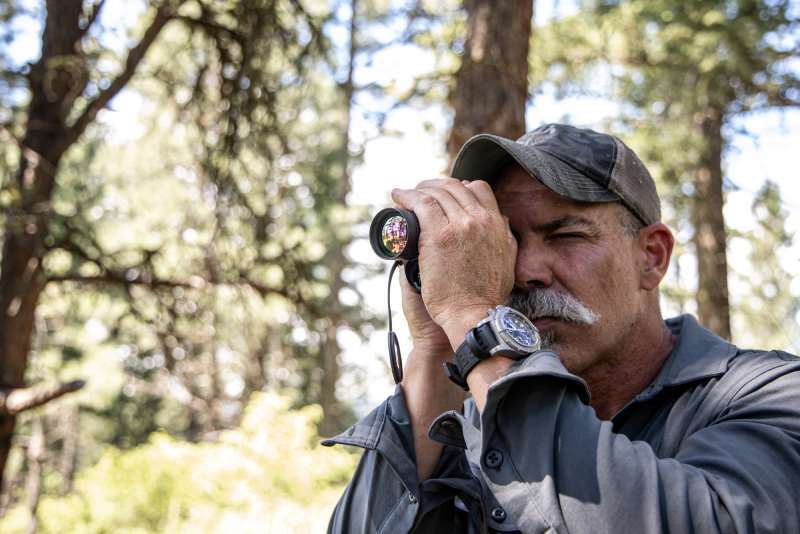 Hunter in the woods using a Bobcat Thermal Imaging Monocular.