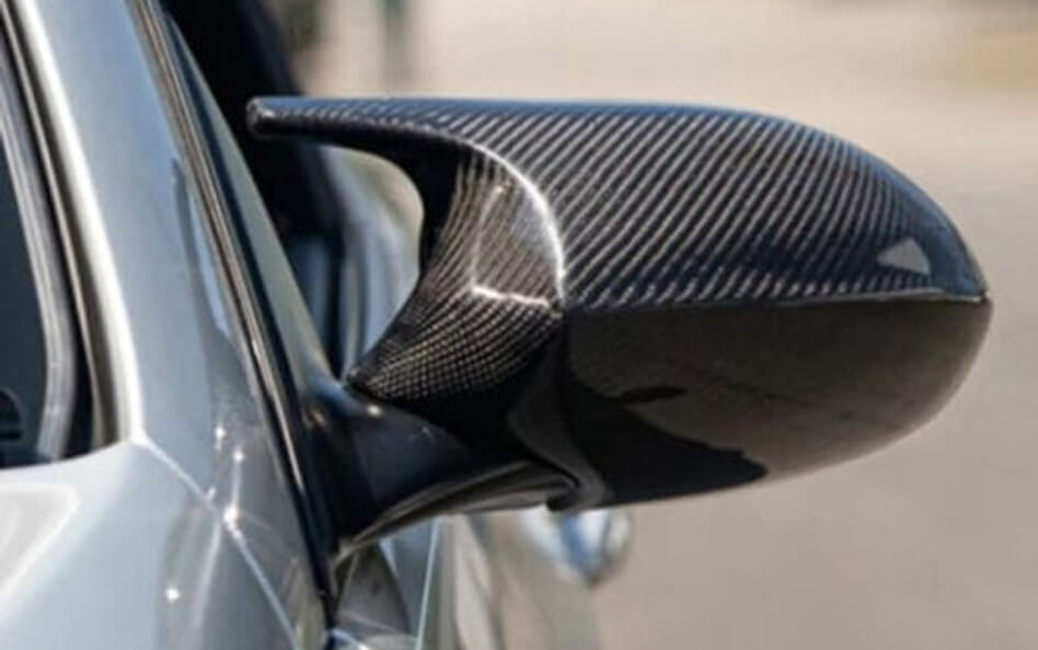 Close-up of a carbon fiber side mirror on a silver BMW.