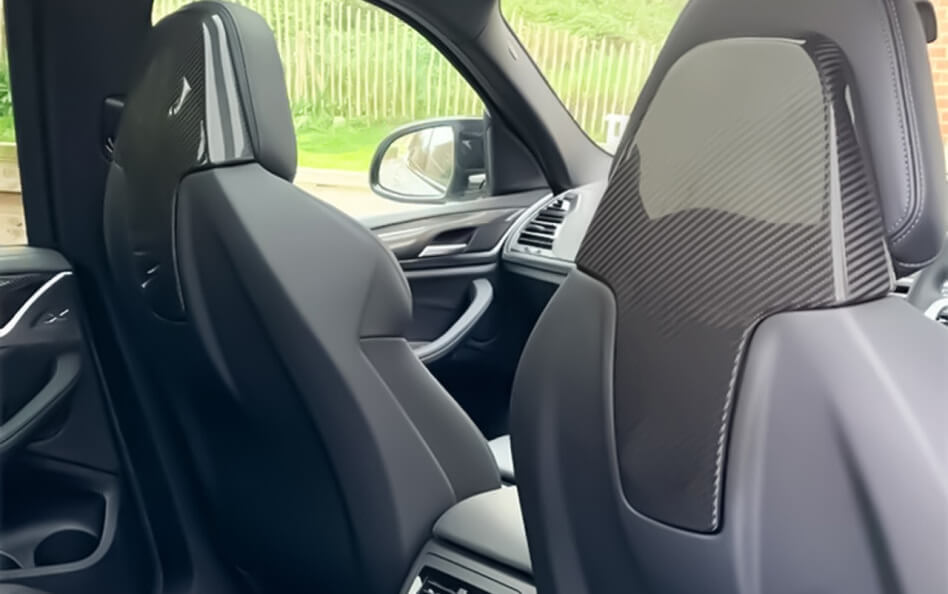 Interior view of a BMW, showing carbon fiber-backed front seats and modern door panel design.
