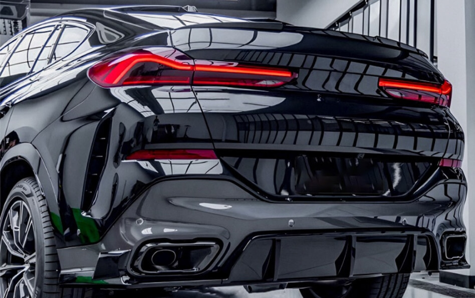 Rear view of a black BMW with sleek LED taillights, quad exhaust tips, and a sporty diffuser design.