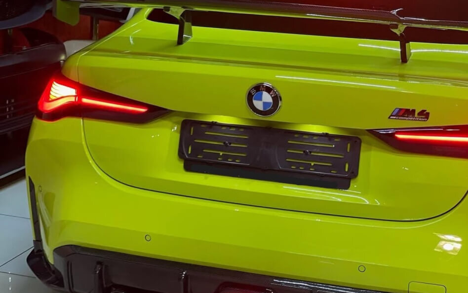 Rear view of a bright lime green BMW M4 CSL, showcasing its distinctive LED taillights, prominent rear spoiler, and aggressive bumper design.