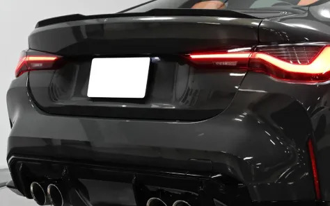 Close-up of a blue BMW with carbon fiber spoiler and modern taillights.