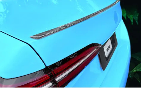 Close-up of a blue BMW with a carbon fiber spoiler and modern taillights.