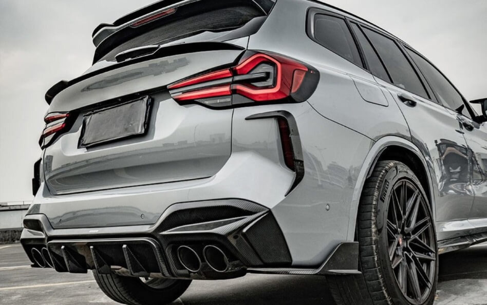 Rear-angle view of a high-performance, silver BMW SAV with aggressive styling elements. The vehicle features quad exhaust tips, a large rear diffuser, tinted windows, and striking LED taillights.