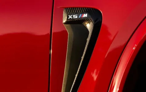 Red BMW X5 M with a focus on the side air vent and badge.