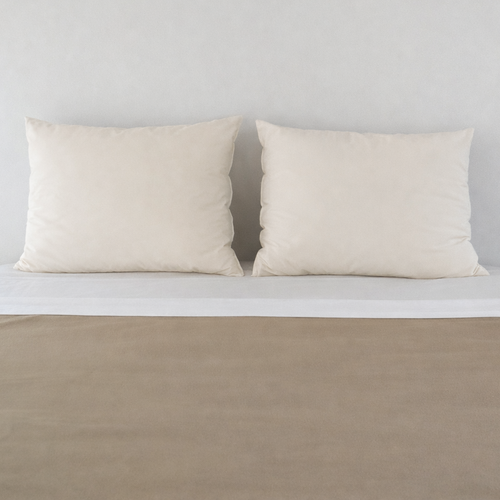 Pair of pillows in natural wheat cotton covers on bed with Polartec blanket