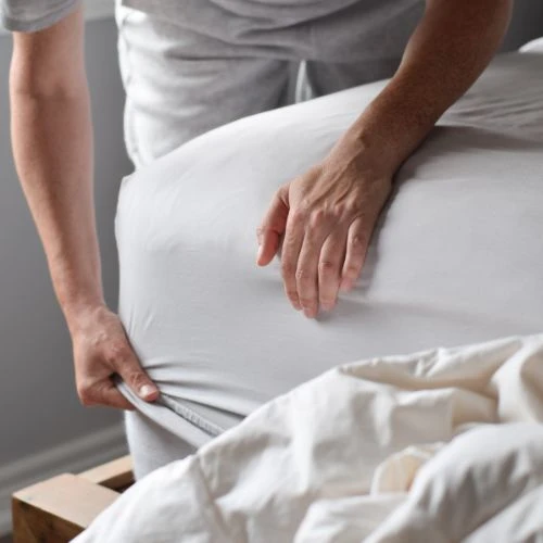 Person putting NoTuck Top Sheet® on bed