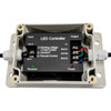 Open weatherproof RGB LED controller enclosure showing the internal control module and wiring connections. The black LED controller is mounted inside a gray waterproof housing, with AC power input terminals on the left and RGB output terminals on the right. Red, green, blue, and black wires are connected to labeled channels, and indicator lights for power and receiver status are visible. Displayed on a white background.