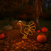 LED rope light turkey sign outside against a hay bail