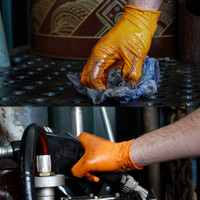 orange nitrile gloves with grip being used by a mechanic working on a vehicle