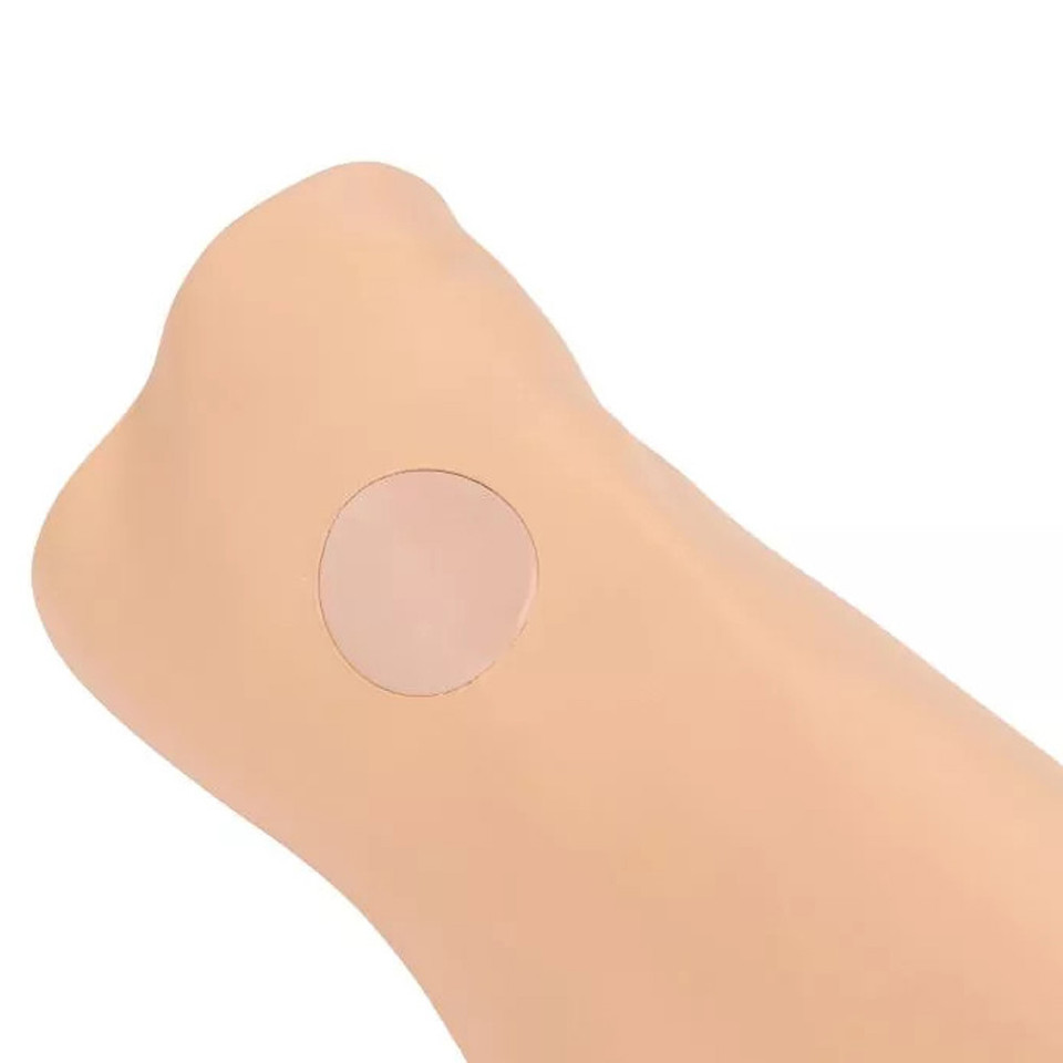 Close-up view of a simulated lower leg showing the circular replaceable intraosseous (IO) puncture pad on the tibial insertion site.