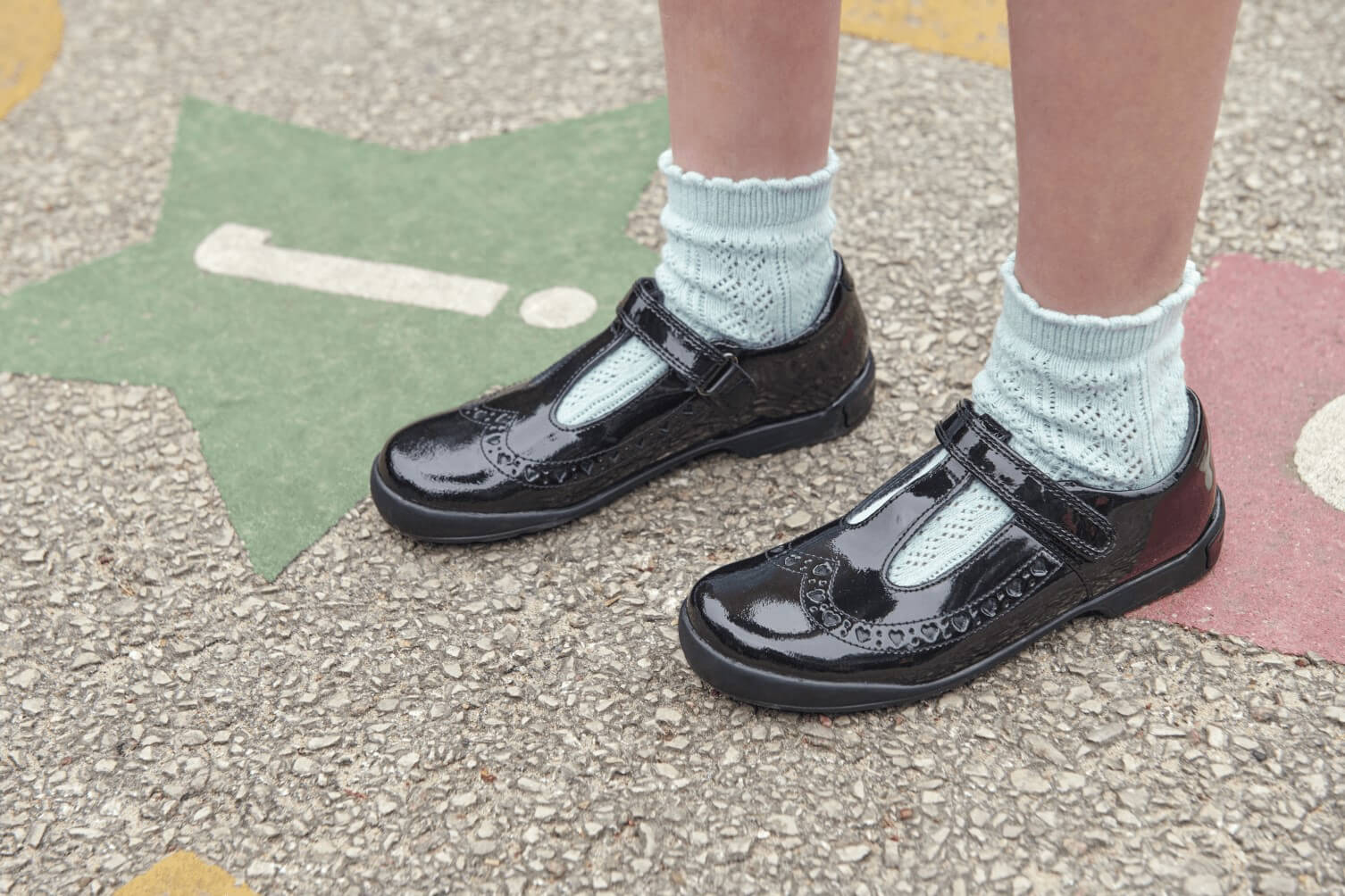 A young girl wearing ankle socks with shiny black school shoes.