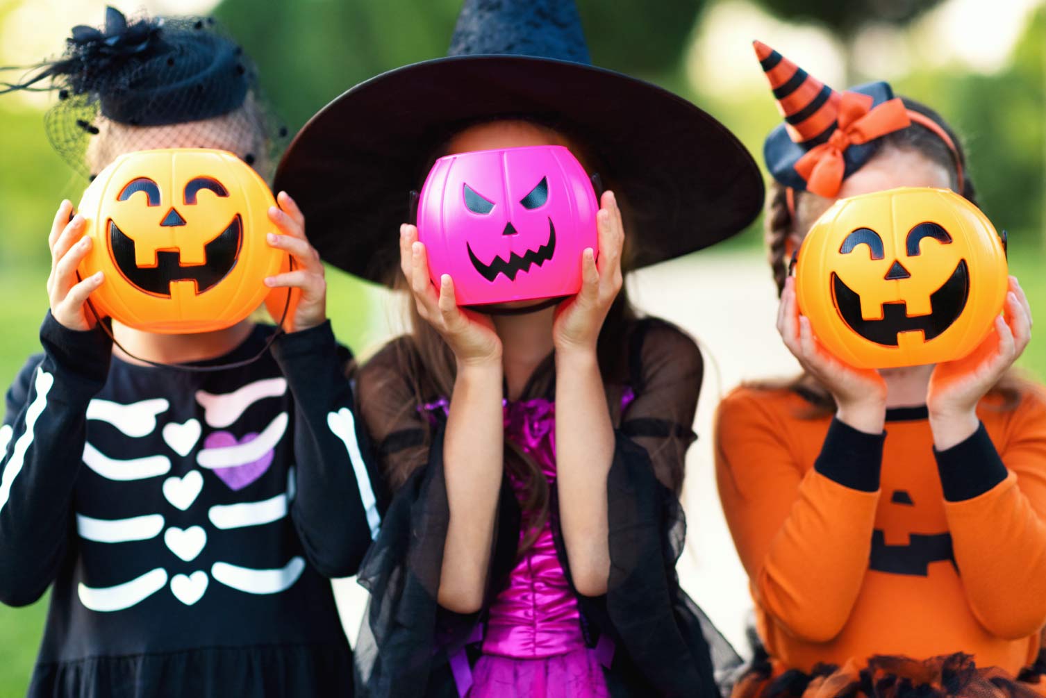 Kids dressed up for Halloween with pumpkins in front of their faces