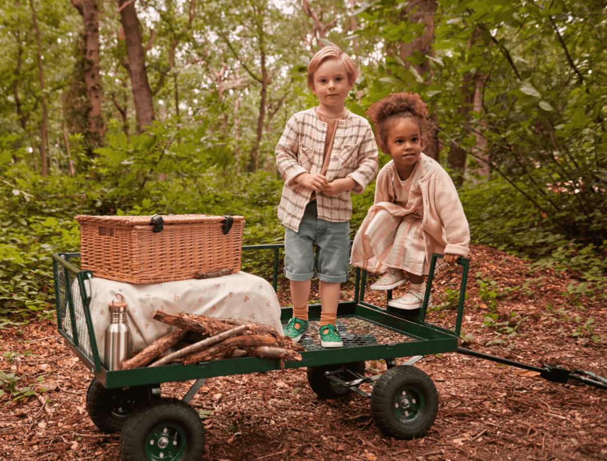 Boy and girl in forest, standing in a pull-along trolley wearing canvas shoes