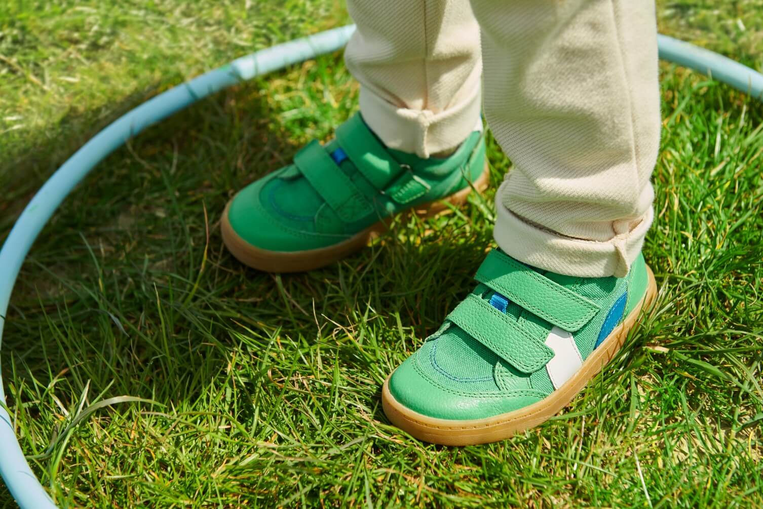 A child in Start-Rite shoes standing on the grass inside a hula hoop