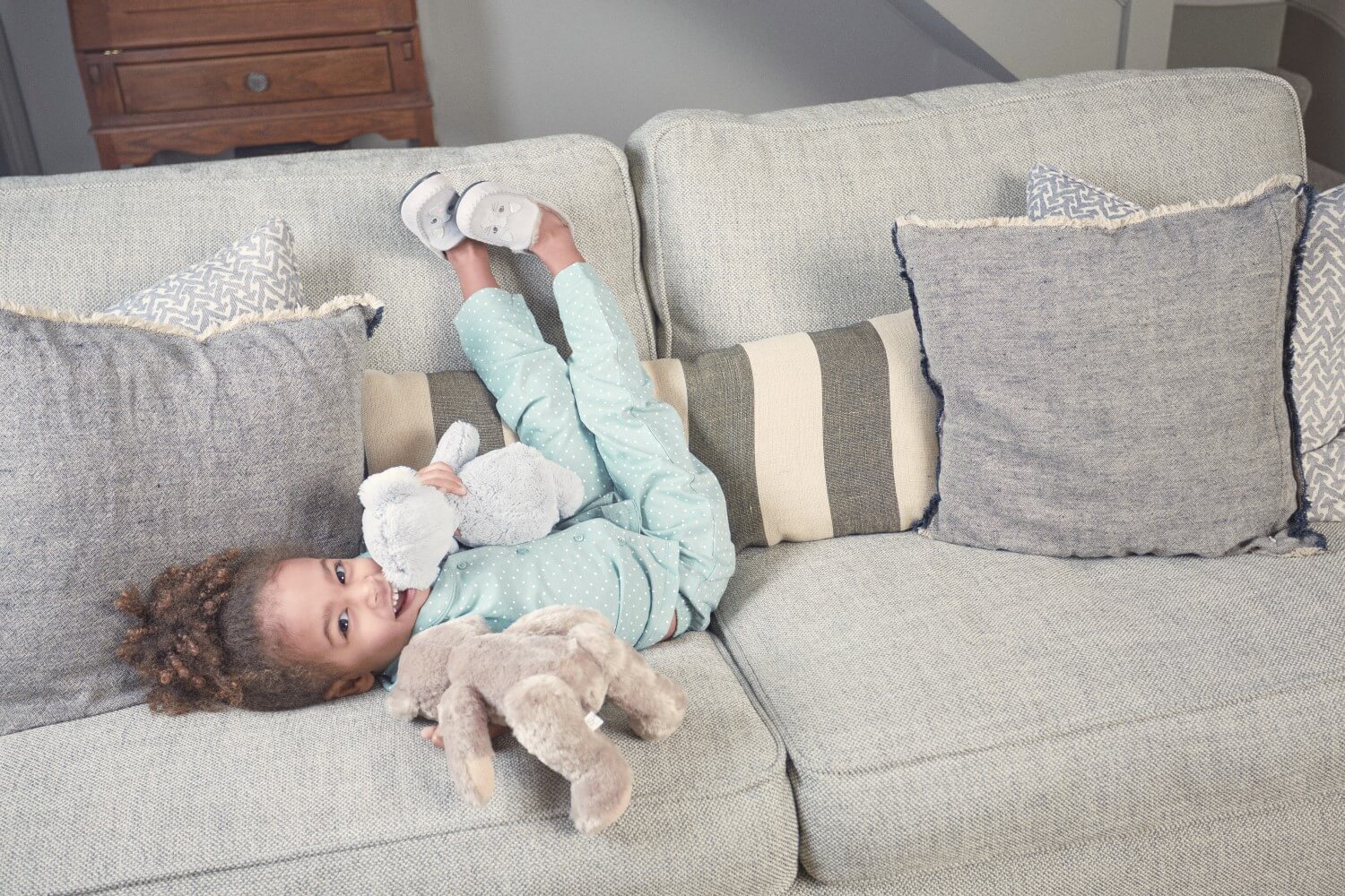 girl in slippers on the sofa with a teddy bear