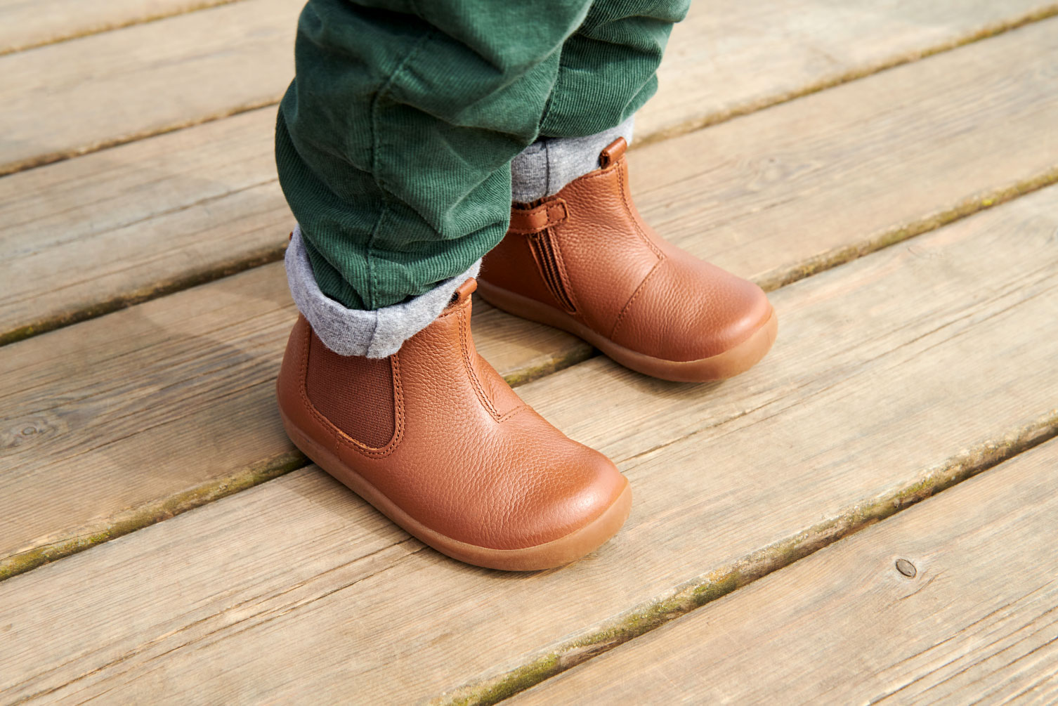 a child stood wearing a pair of tan coloured boots