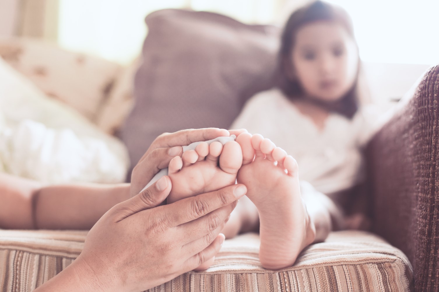 A parent checks their daughter’s feet for injury or infection..