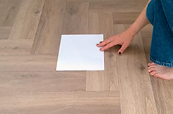 Image of a parent placing a sheet of blank A4 onto a wooden floor