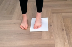 Image of child's sockless foot on a piece of A4 paper, which is on a wooden floor.
