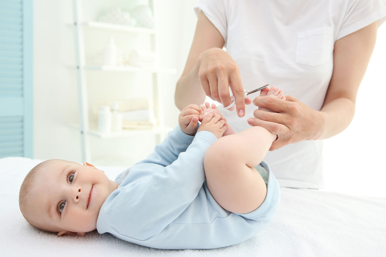 baby on a mat getting nails clipped