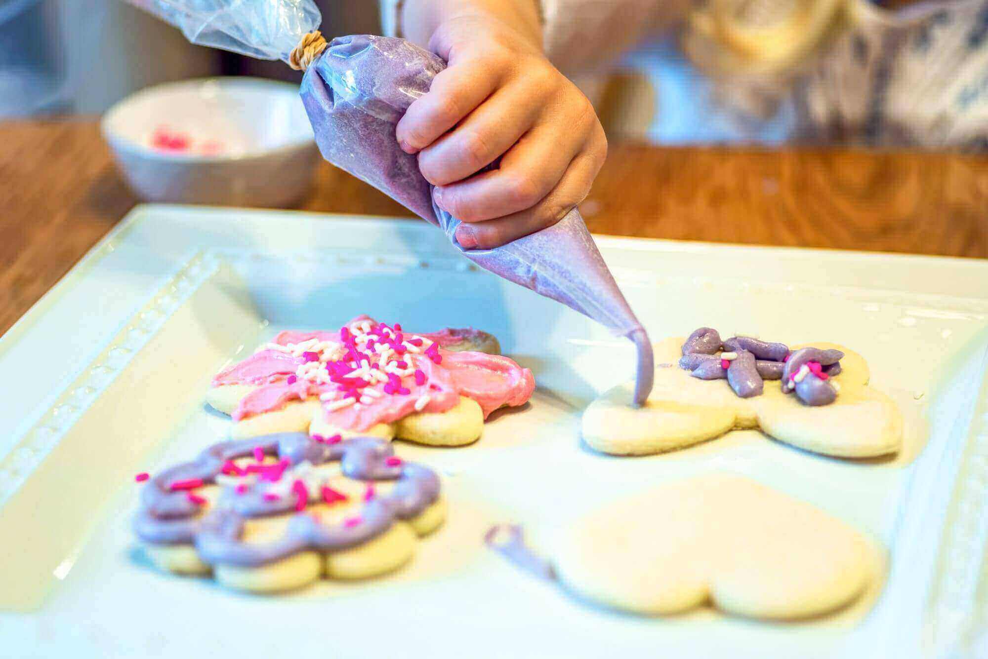 a child decorating biscuits with icing at home