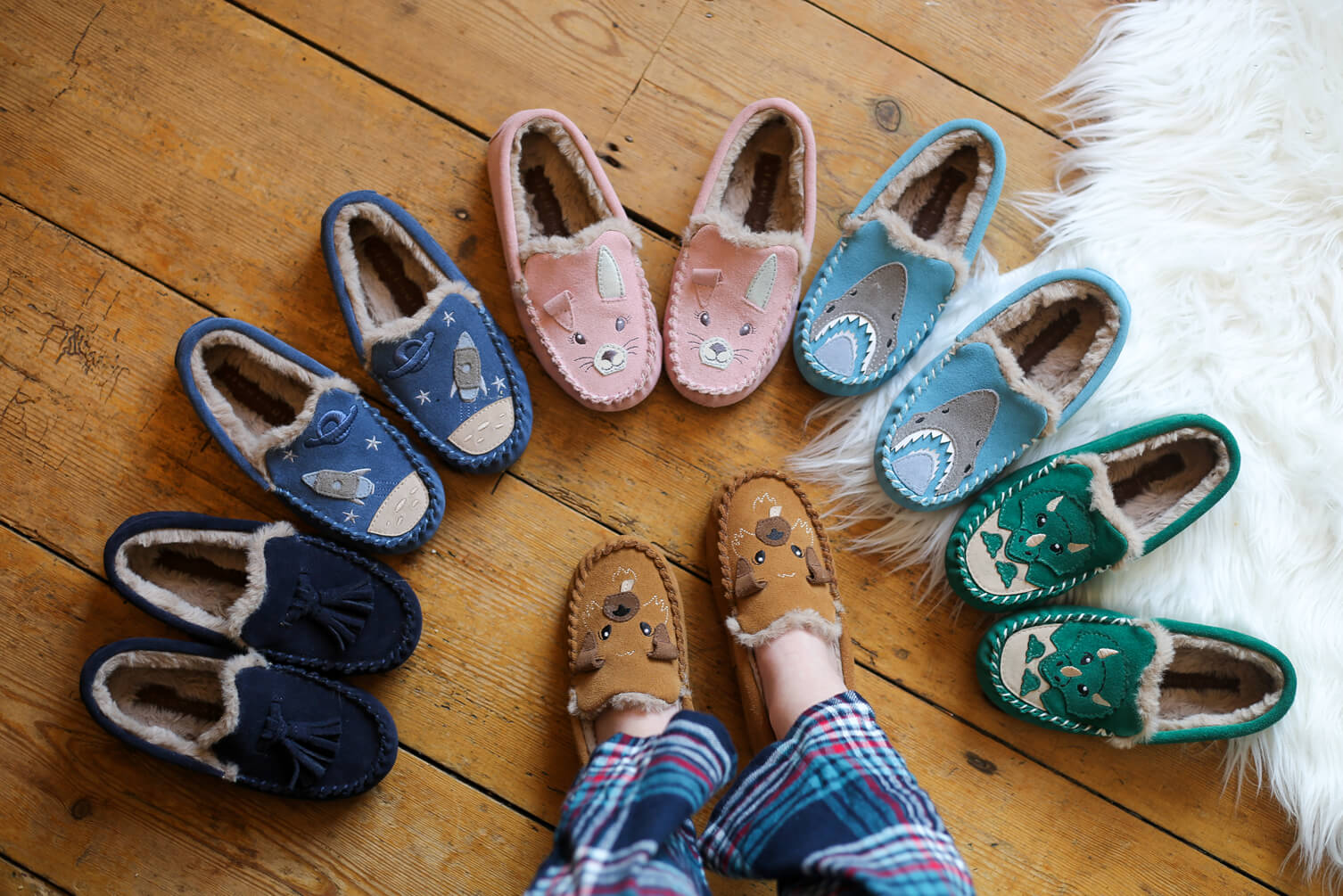 Boy in slippers looking down at other slippers all around him