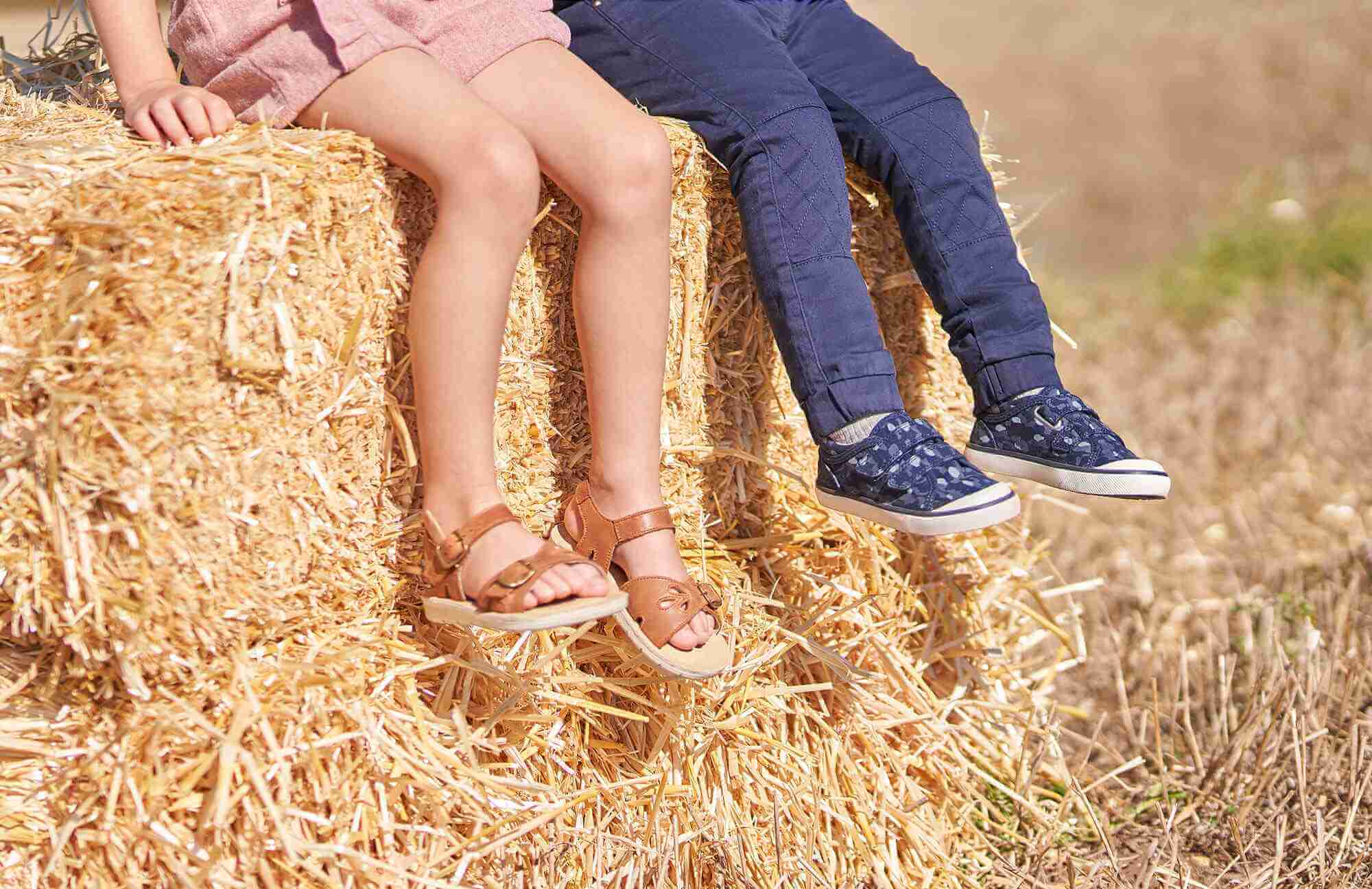 Girl and boy sitting on hay bale