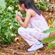 Lifestyle photo of a girl smelling flowers, wearing the Kristin Lilac Purple