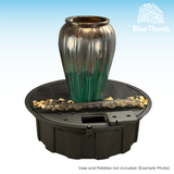 Vase Example Only - A decorative vase sits atop a round fountain basin with small stones and a mesh cover. The vase features a metallic gradient from silver to green. The logo "Blue Thumb" is at the top right.