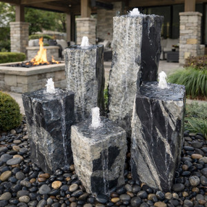 Five-column black flower granite fountain kit with illuminated bubbling water feature in landscaped garden