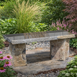 Basalt Bench - 48" - A stone bench sits in a lush garden surrounded by green foliage, pink flowers, and ornamental grass, creating a serene and tranquil atmosphere.