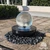 14-inch Crystal Sphere Fountain flowing over a black steel bowl surrounded by polished black pebbles