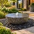 Blue Thumb Natural Bowl Fountain with bubbling water and textured dark stone finish, surrounded by black polished pebbles in a luxury modern courtyard landscape.