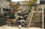 Natural stone cascading waterfall with multiple drops installed beside an outdoor staircase and landscaped garden