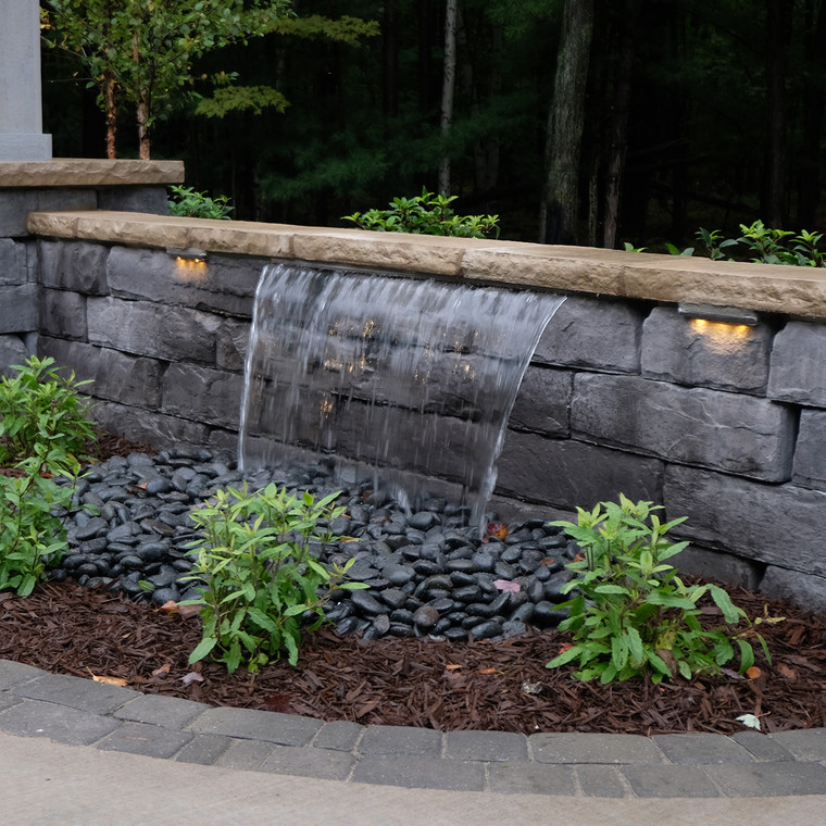 Blue Thumb Medium Formal Falls 28-inch waterfall installed in a stone retaining wall with water cascading into a concealed basin