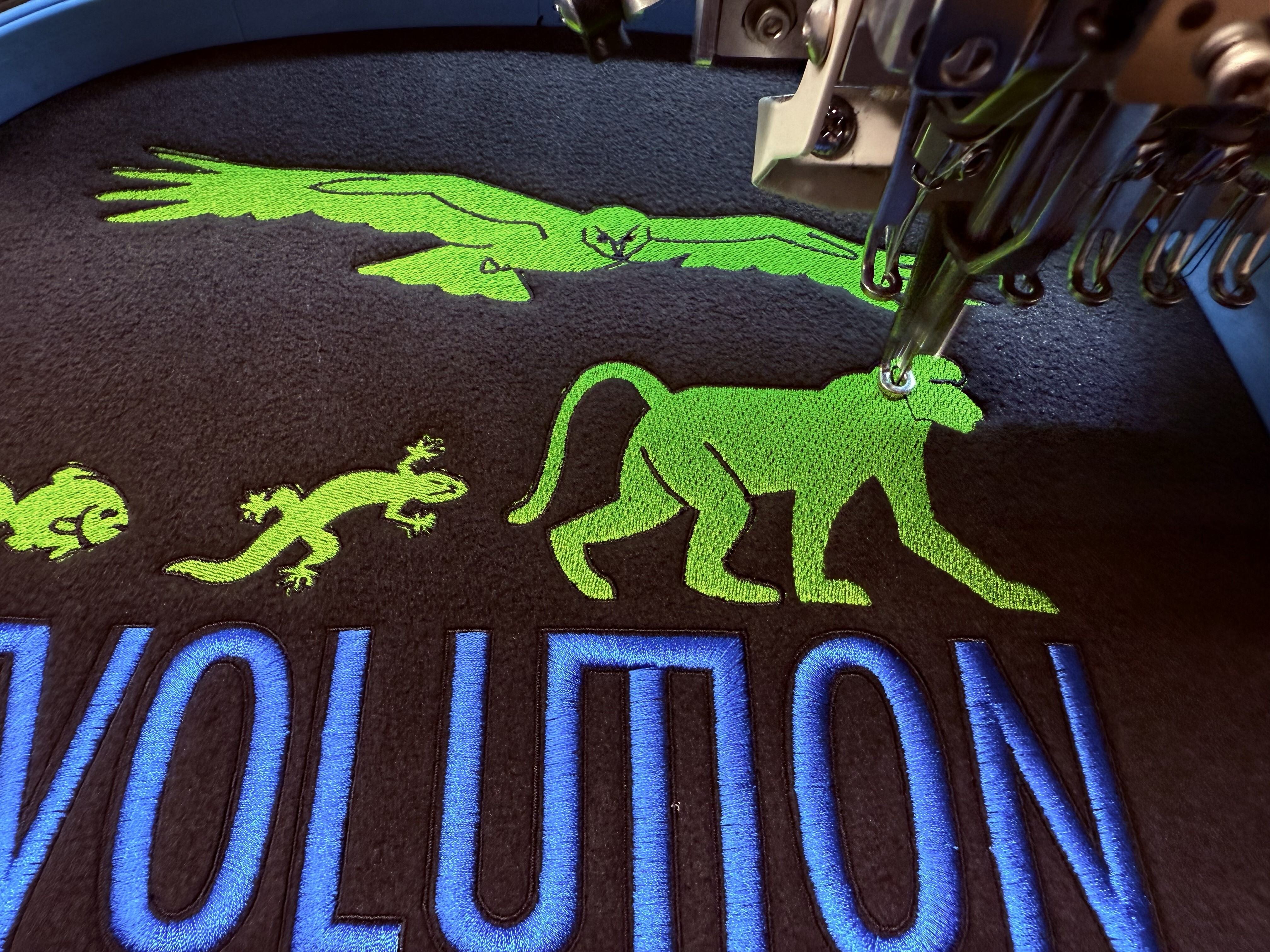 Close-up of logo embroidery being stitched onto a black workwear fleece