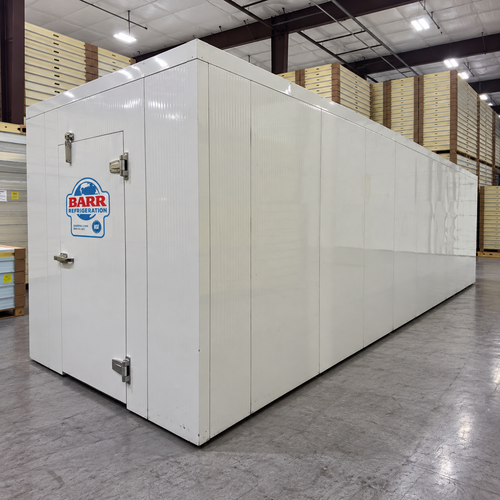 White walk-in cooler unit with closed hinged door, featuring insulated panel walls front right view
