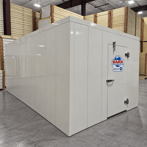 White walk-in cooler unit with closed hinged door, featuring insulated panel walls front left view
