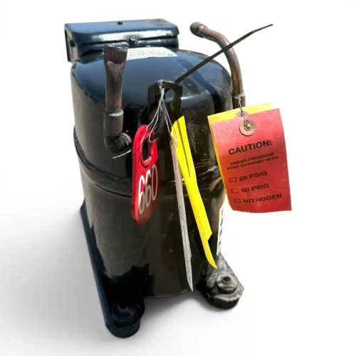 Top-angled view of a used Copeland RS64C2-CV .75 HP compressor (1 phase 208-230 volt), a black reciprocating compressor with multiple hang-tags including a red "660" inventory tag, a yellow "OIL SAFETY CONTROL" tag, and a red "CAUTION: UNDER PRESSURE" tag on the top service valve.