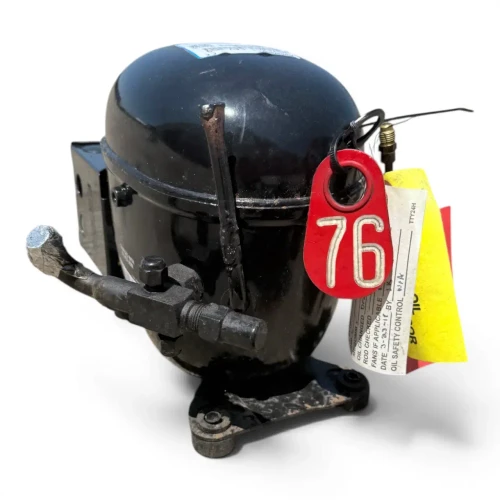 Front-angled view of a used Copeland RS64C1-CAV .75 HP compressor (1 phase 208-230 volt), a black reciprocating compressor with yellow and red hang-tags at upper left, an orange "WARNING/CAUTION" label on the front of the shell, and the metal terminal box on the right side.
