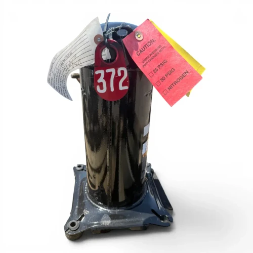 Close-up top view of the used Copeland ZB07KAE-PFV .8 HP compressor, showing the red "372" tag, the white service checklist tag, and the red/yellow caution tags gathered at the dome, with the black cast base visible below.