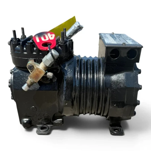 Front-angled view of the used Copeland KARA-010E-TAC 1 HP compressor (mirrored/reversed orientation), showing the yellow "ADD OIL TO COMPRESSOR" tag and a partially visible red tag near the top service valves, with the terminal box on the left.